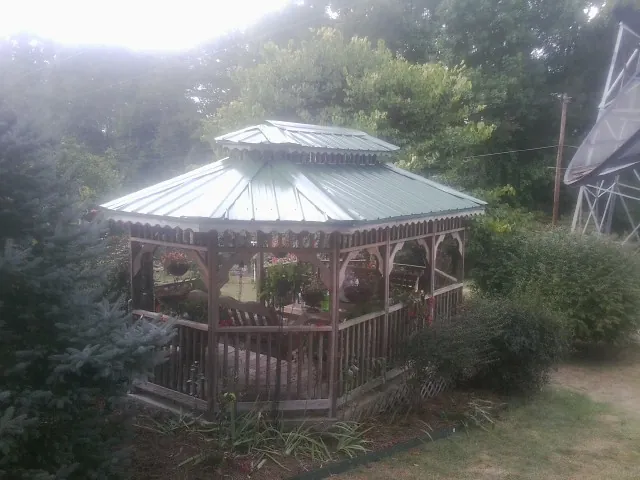 Green metal roof on a backyard gazebo surrounded by garden beds in Centreville