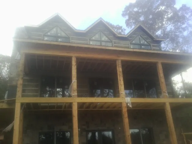 Dormers and porch framing on a large log home under construction — Roof Coating work by our crew in Centreville